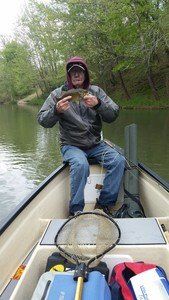 A man is sitting in a boat holding a fish.