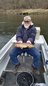 A man is sitting on a boat holding a fish.