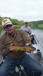 A man is sitting in a boat holding a fish.