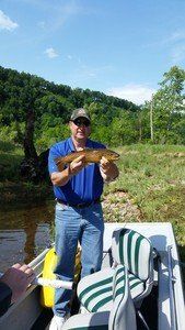 A man is standing on a boat holding a fish.
