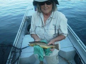 A woman in a boat is holding a fish