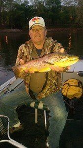 A man is sitting on a boat holding a large fish.