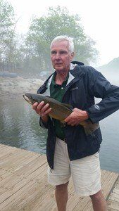 A man is holding a fish on a dock.