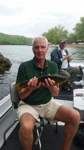A man is sitting on a boat holding a fish.