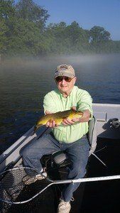 A man is sitting on a boat holding a fish.