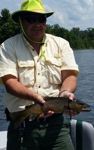 A man in a yellow hat is holding a fish in his hands