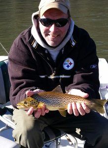 A man wearing a jacket with the word steelers on it is holding a fish