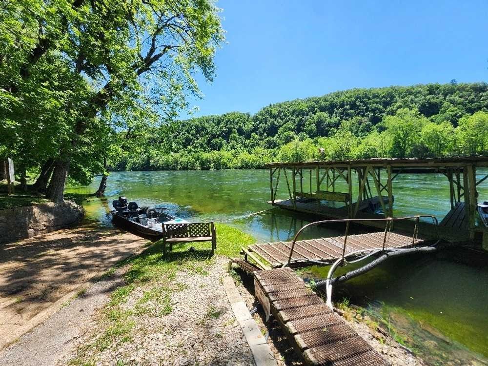 A boat is docked at a dock on a lake surrounded by trees.