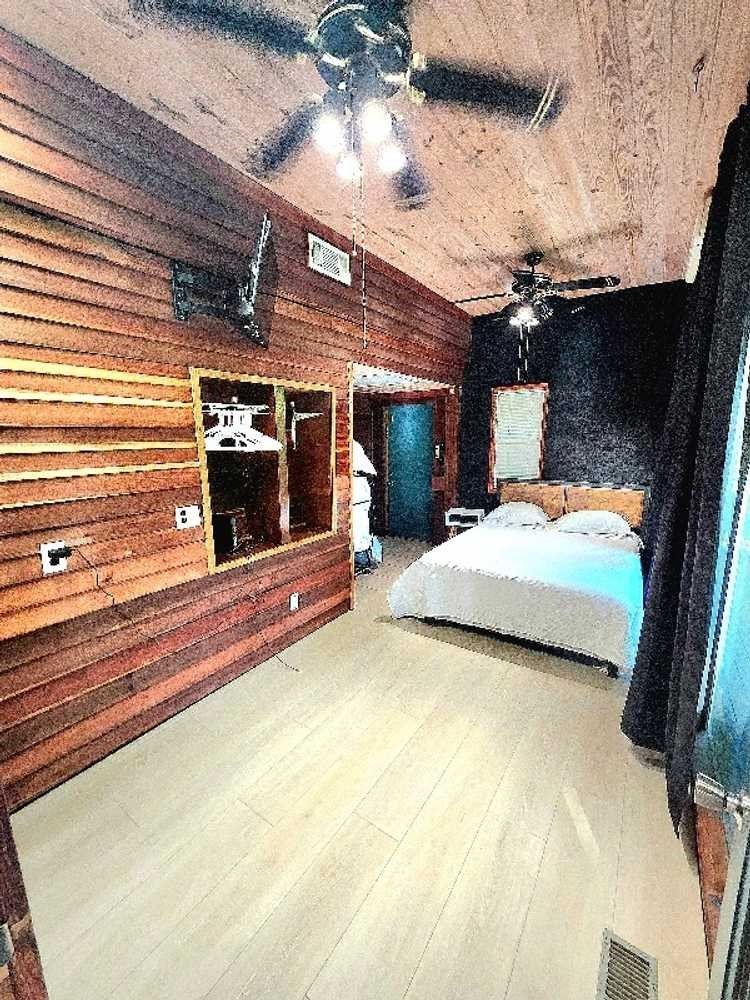 A bedroom with a bed and a ceiling fan.