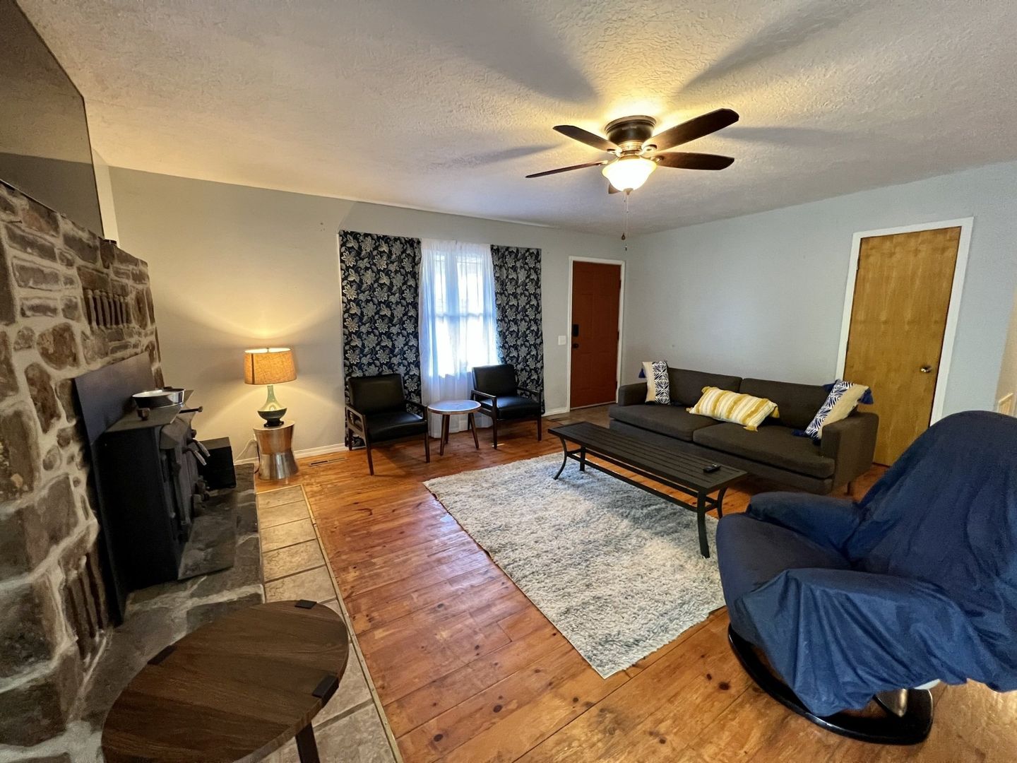 A living room with a couch , chair , table , fireplace and ceiling fan at copper johns resort