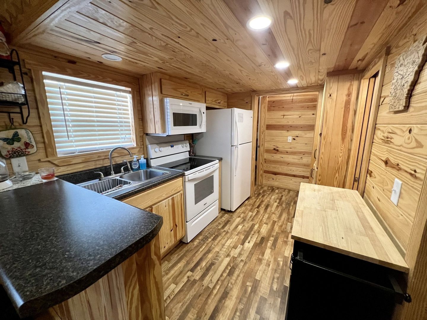 A kitchen in a log cabin at copper johns resort with a stove , refrigerator , microwave and sink.