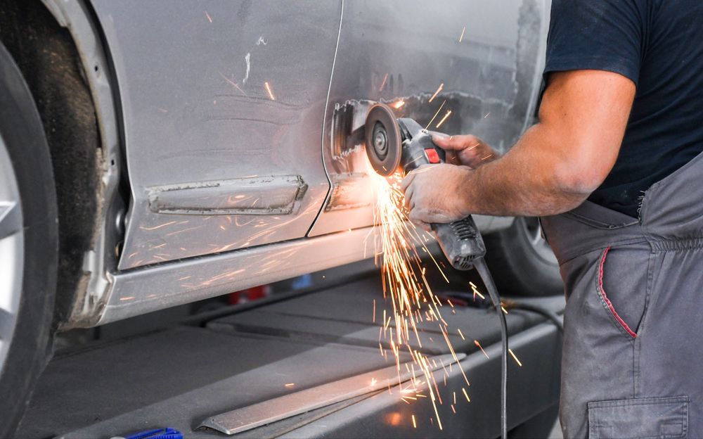 A Person Using a Grinder on a Car Door, Sparks Flying, Working in a Repair Shop — Cairns Metal Works in Portsmith, QLD