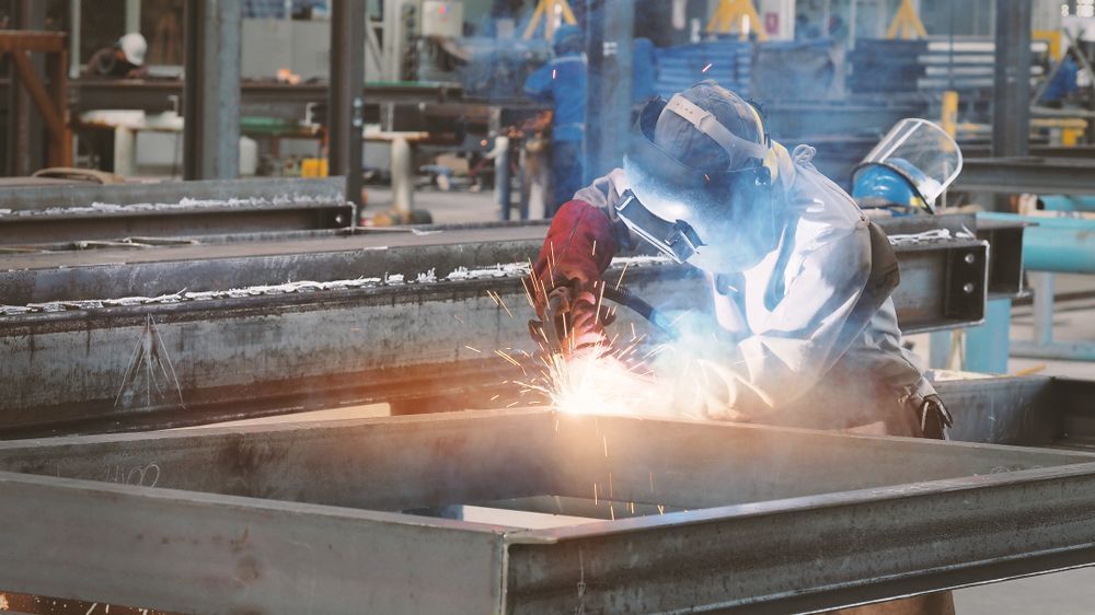 Welder in Protective Gear Welding Metal Beams in a Factory — Cairns Metal Works in Portsmith, QLD