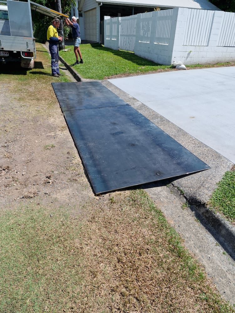 A Long, Dark Ramp Slopes Down From the Curb to the Street, With Two Men Nearby — Cairns Metal Works in Portsmith, QLD