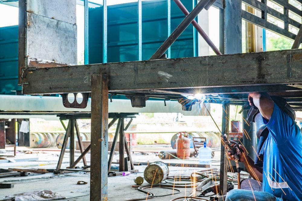 Welder in Blue Shirt Welding Metal Framework — Cairns Metal Works in Portsmith, QLD