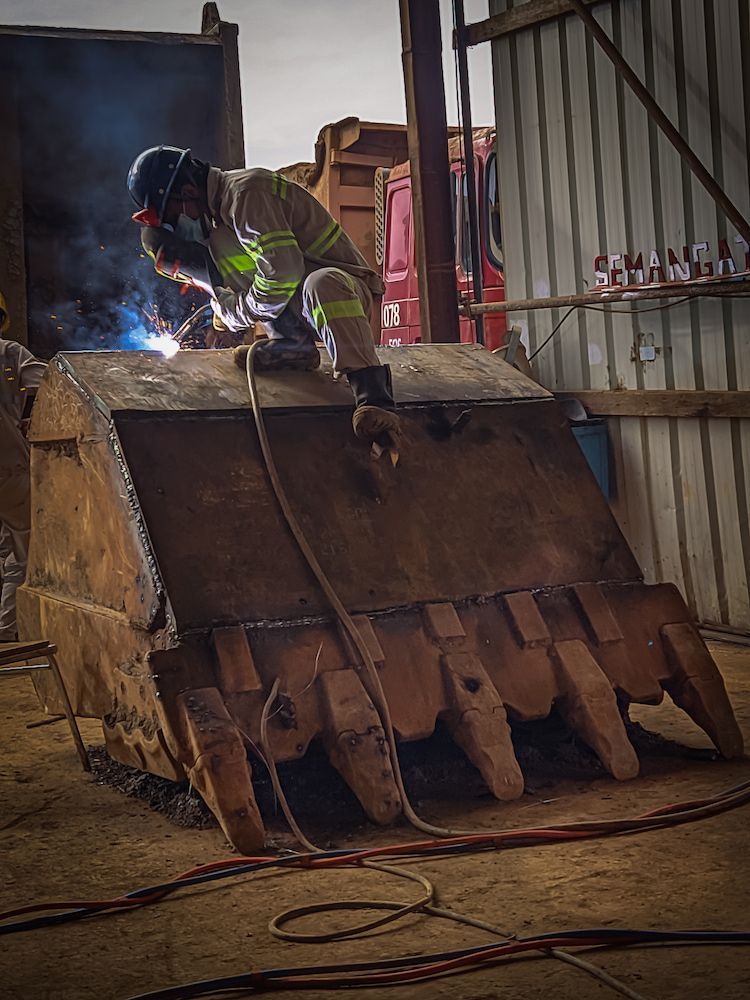 Welder in Protective Gear Working on a Large Metal Excavator Bucket, in a Workshop — Cairns Metal Works in Portsmith, QLD