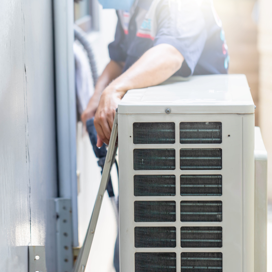 HVAC technician in a mask working on an air conditioning unit outside.