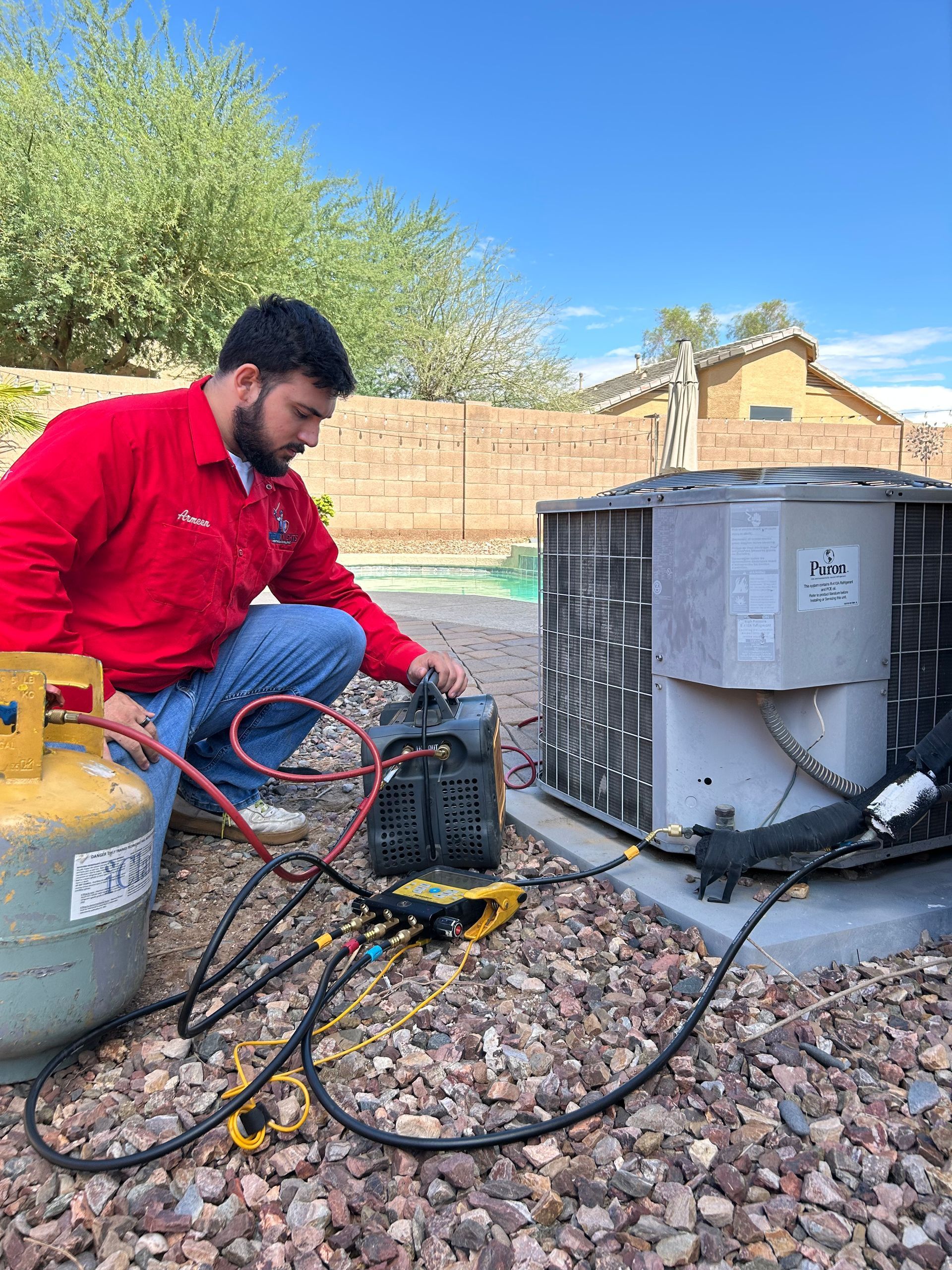 Technician connecting refrigerant lines to an air conditioner unit outdoors.
