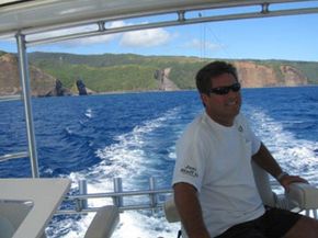 A man wearing sunglasses is sitting on a boat in the ocean