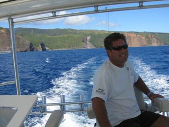 A man wearing sunglasses is sitting on a boat in the ocean