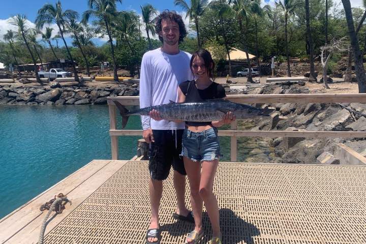 A man and a woman are holding a large fish on a dock.
