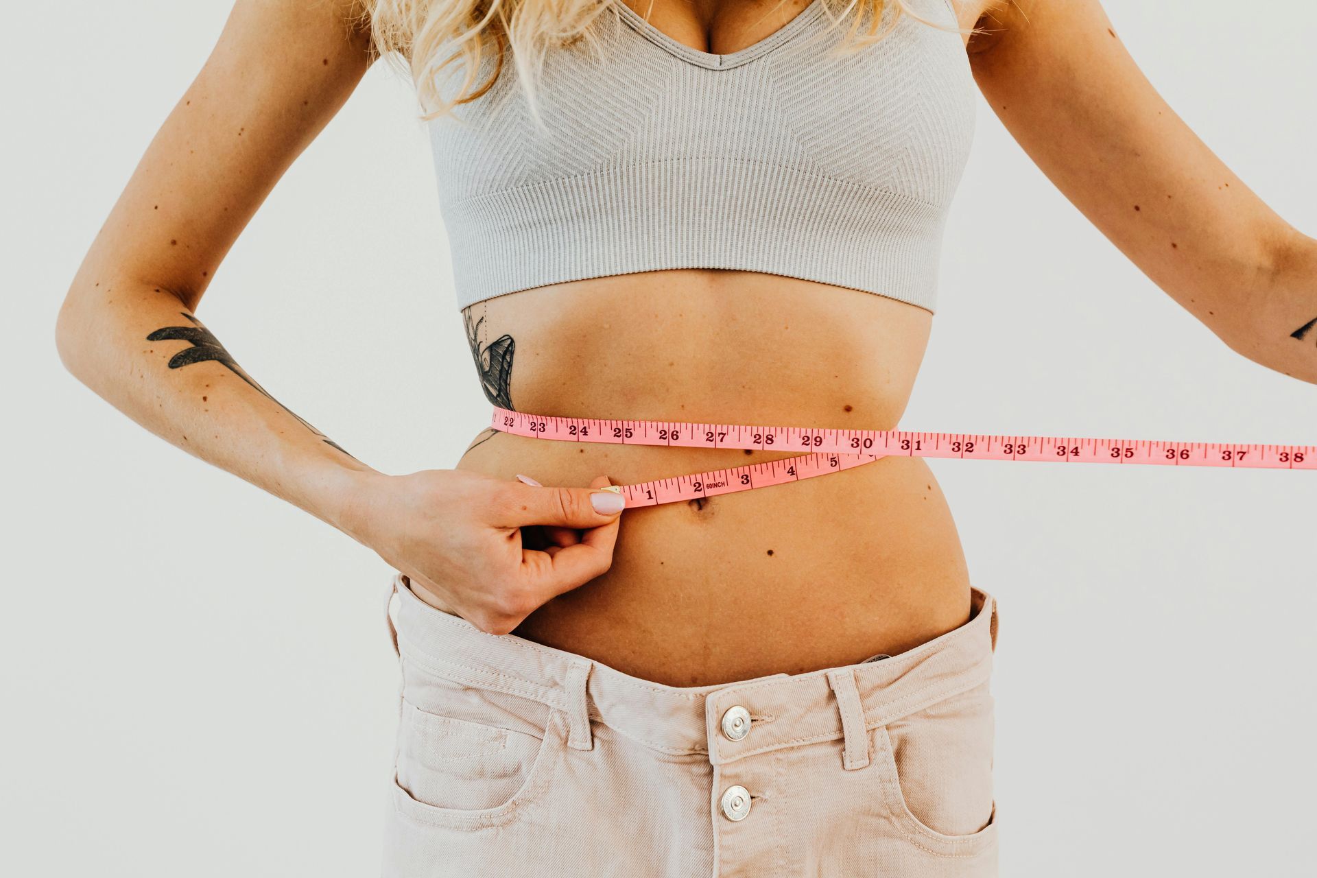 A woman is measuring her waist with a tape measure.