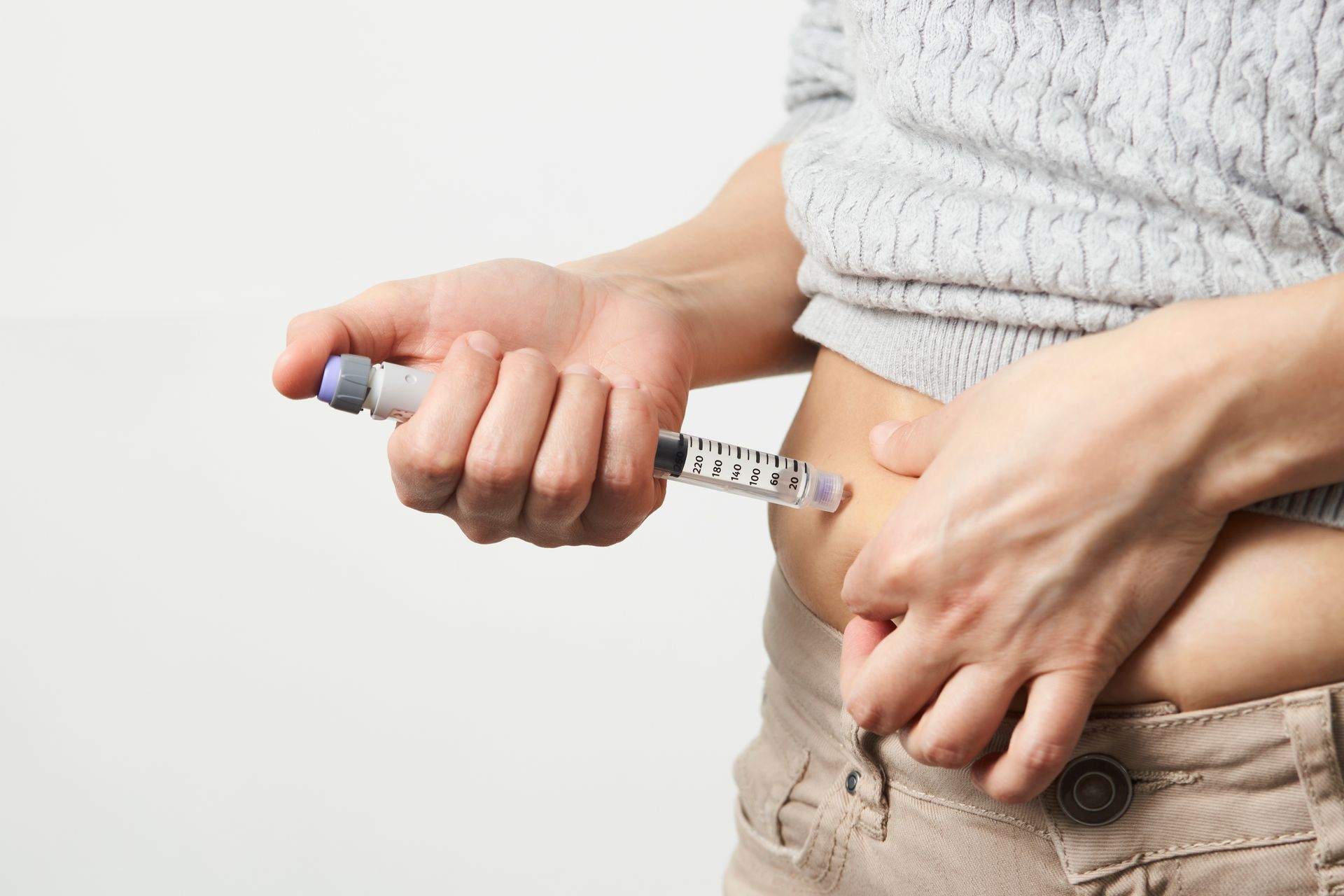 A woman is getting an insulin injection in her stomach.