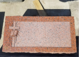 Stone slab with a carved rectangular inset and small cross-like marks on the left, on a work surface