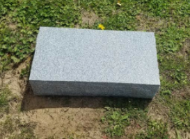 Gray rectangular stone block on grass in an outdoor setting