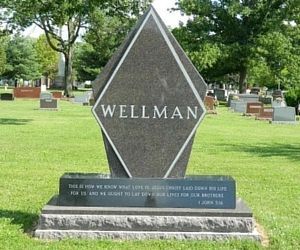 Wellman gravestone in a green cemetery, featuring a tall dark monument with white lettering.