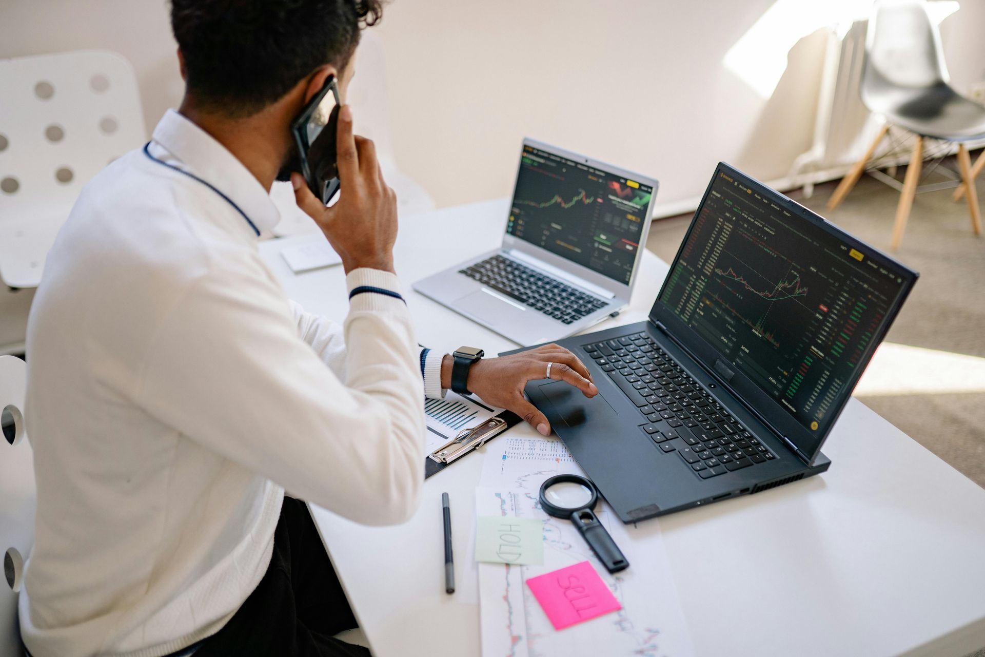Man Talking on Phone and Working on Laptops
