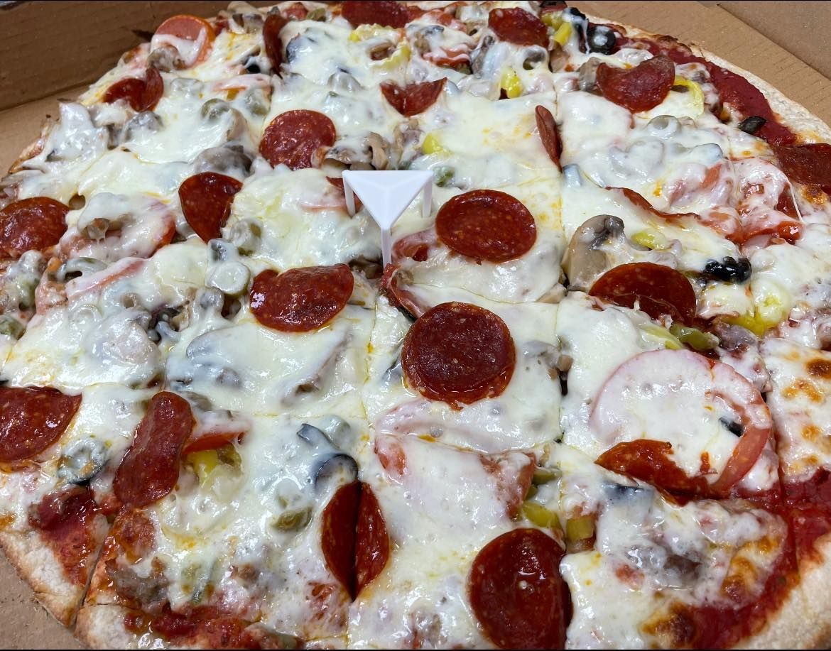 A pizza with pepperoni , mushrooms , olives and cheese is in a box.