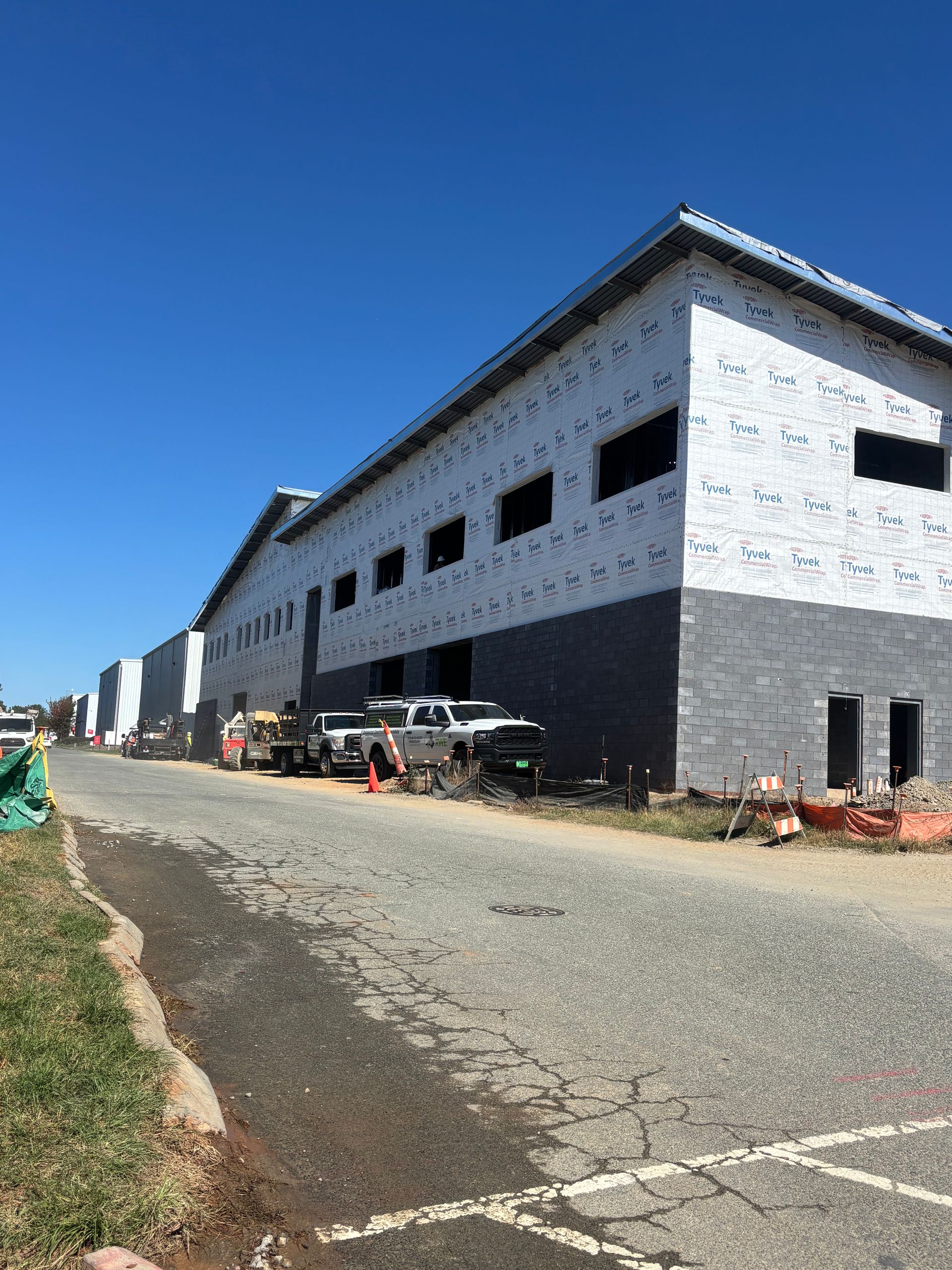 Building under construction with white siding and gray brick on a sunny day.
