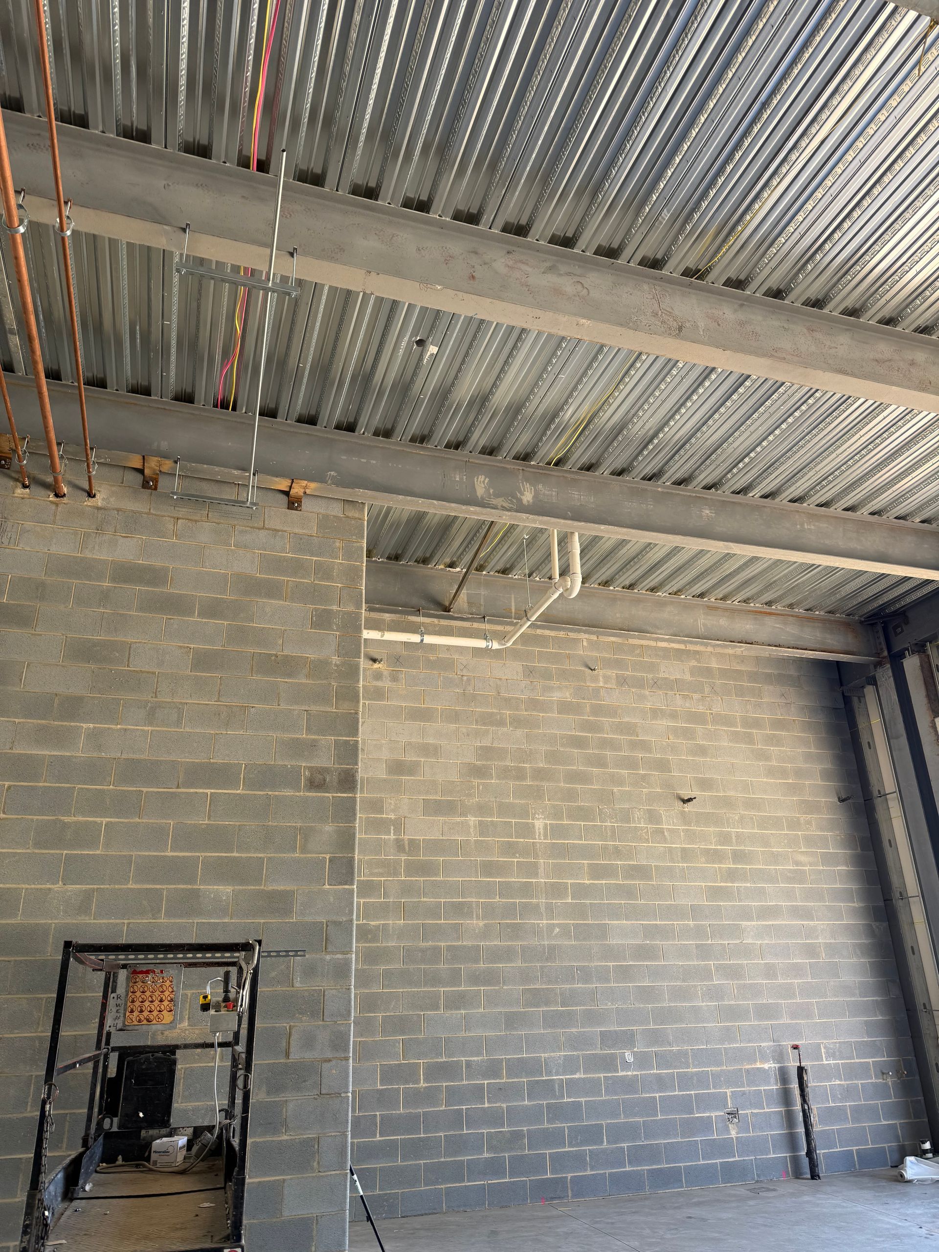 Interior of unfinished construction site with gray cinder block walls and corrugated metal ceiling.