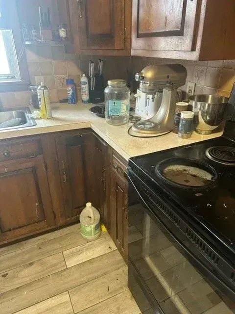 Kitchen with dark wood cabinets, appliances, and a jar of water on the countertop next to a stand mixer