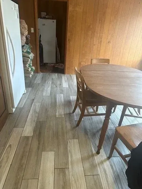 Dining room with a wooden table and chairs, a new wood-look floor, and an open doorway to another room