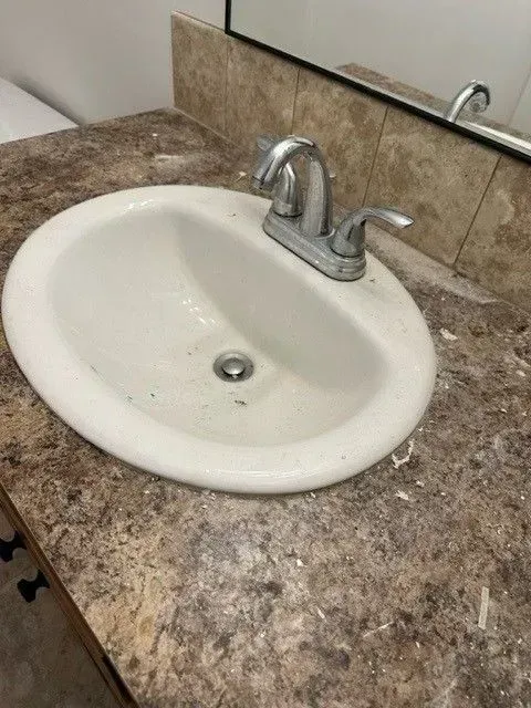 White oval sink with a chrome faucet on a brown countertop