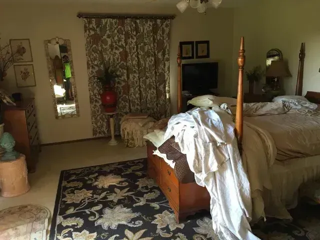 Bedroom with a four-poster bed, floral curtains, a rug, and a dresser