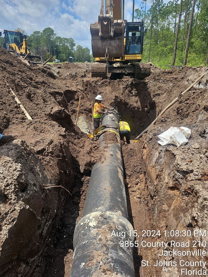 two workers attaching large DI pipes together