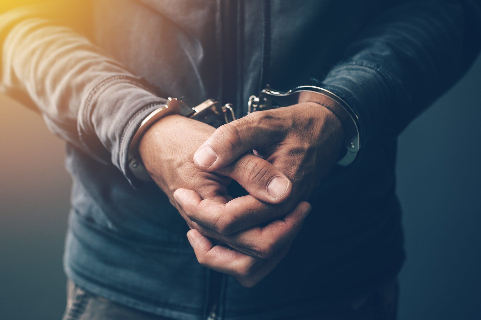 Arrested computer hacker and cyber criminal with handcuffs, close up of hands