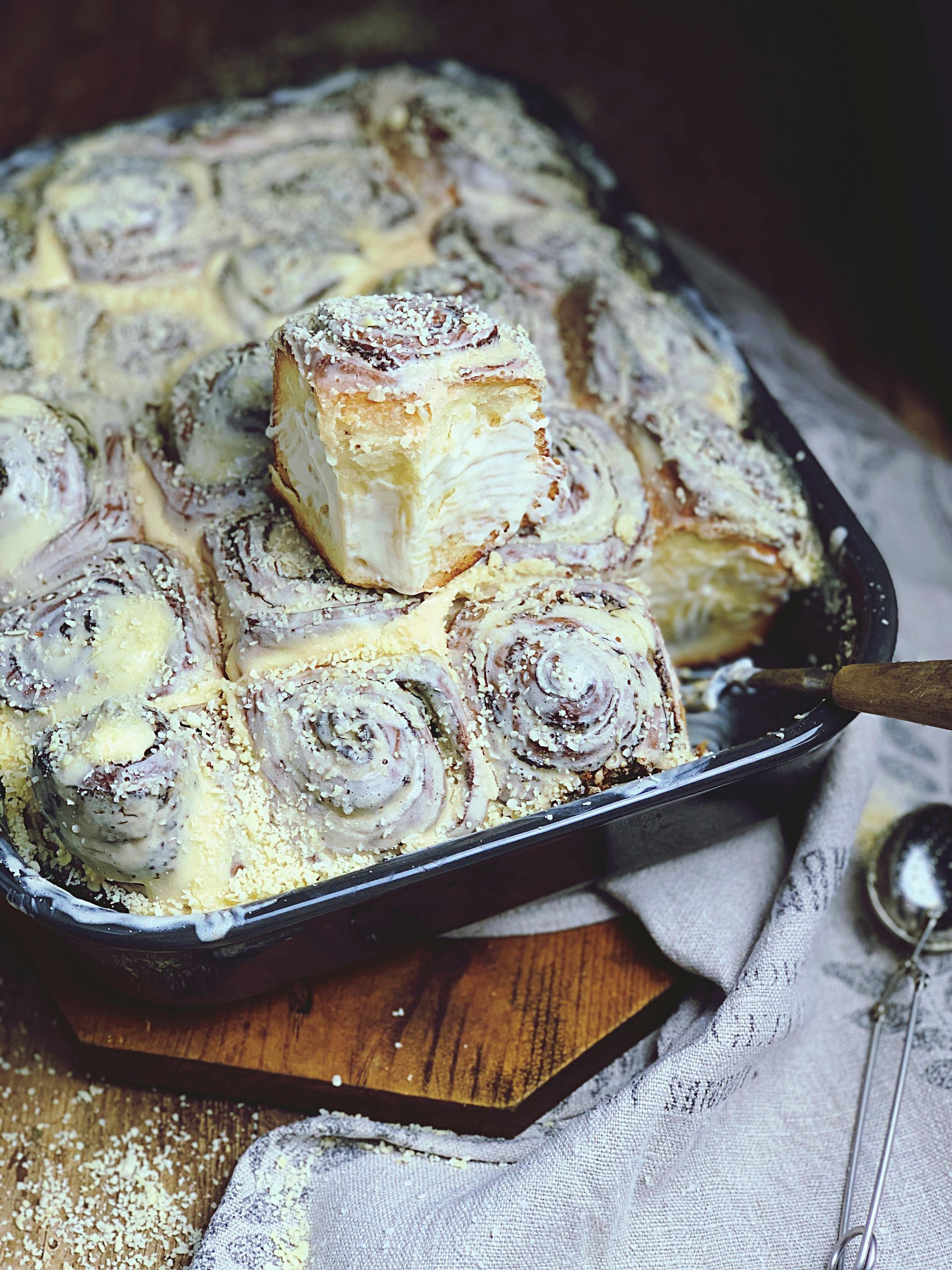 A pan of cinnamon rolls with a spoon in it on a table.
