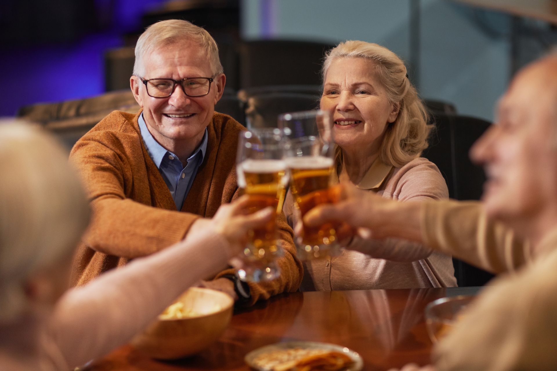 A group of older people toasting with glasses of beer