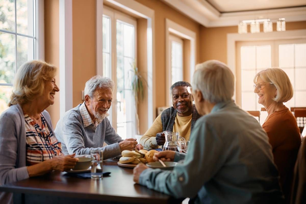 Five 55+ people share a meal and laughter in their community near Cincinnati, Ohio (OH)
