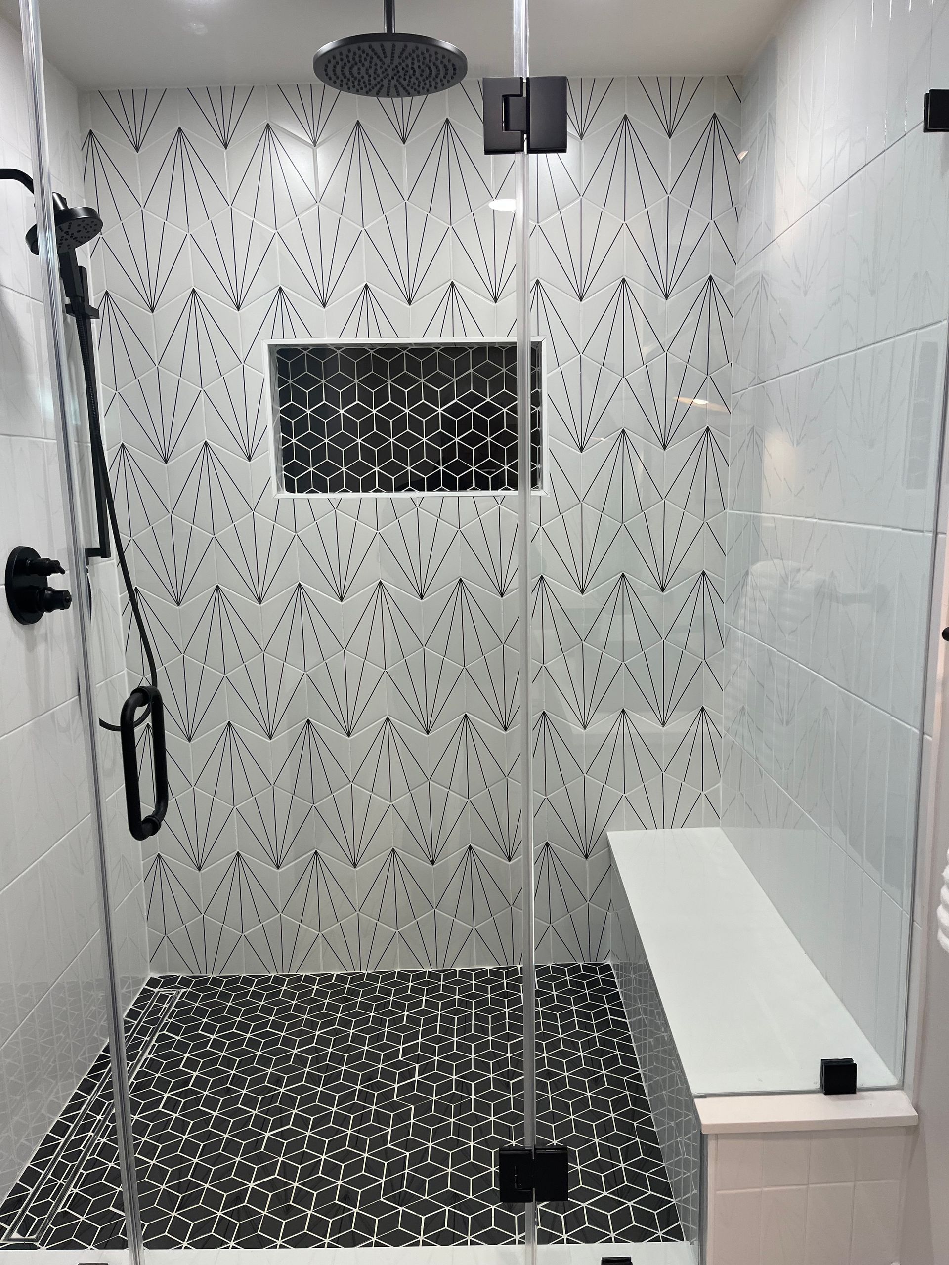 A bathroom with a walk in shower with a glass door and a bench.