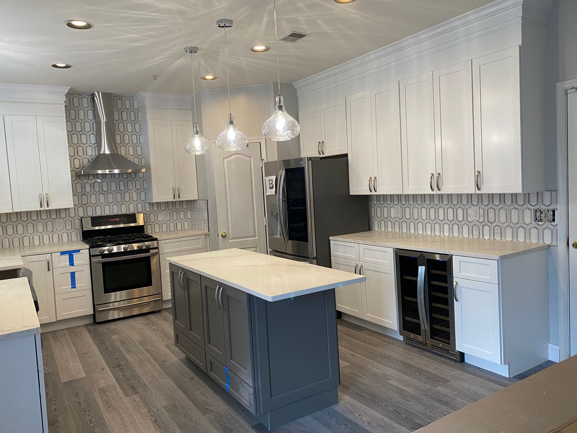 A kitchen with white cabinets , stainless steel appliances , and a large island.