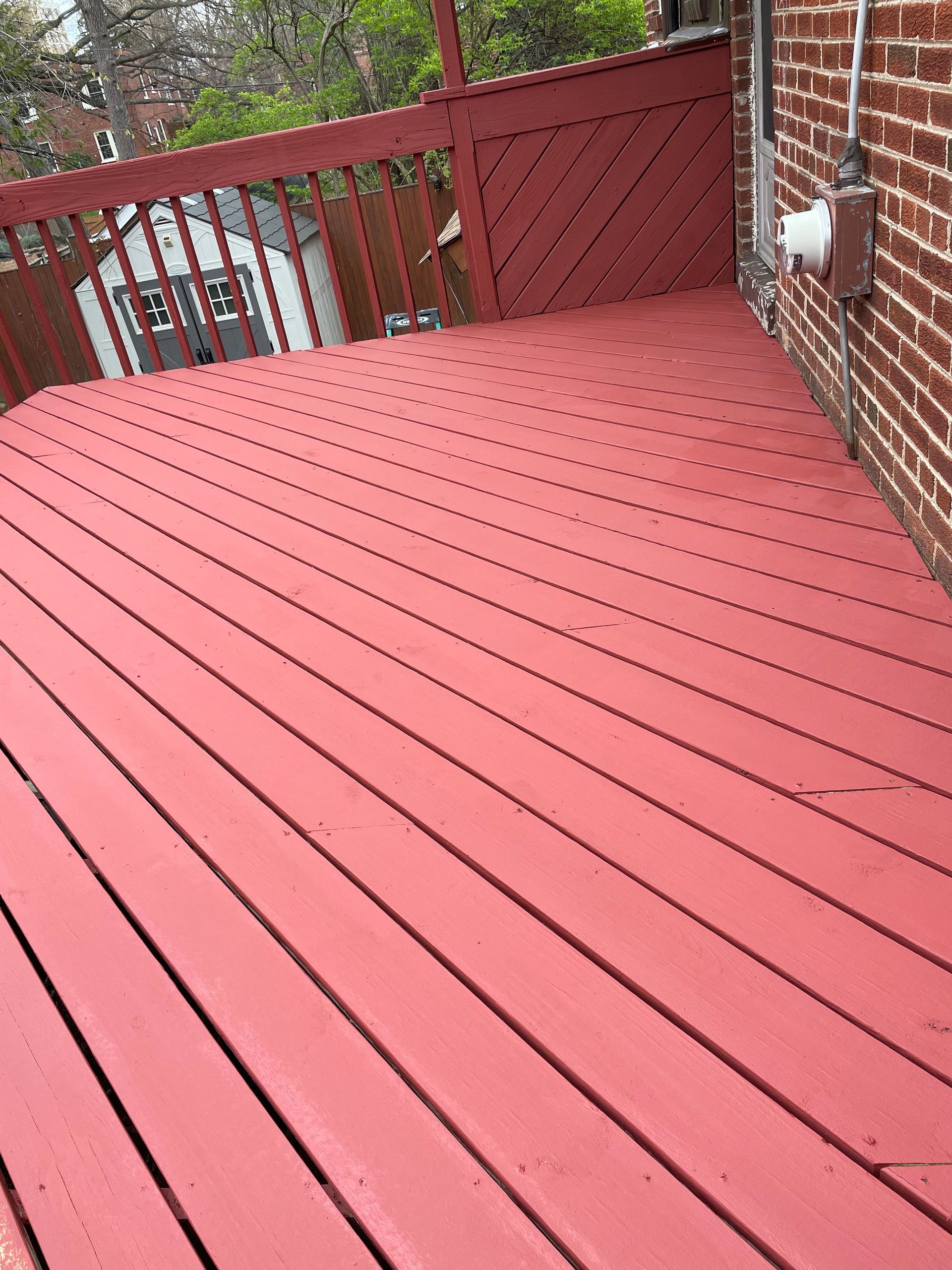 A red wooden deck with a brick wall in the background.