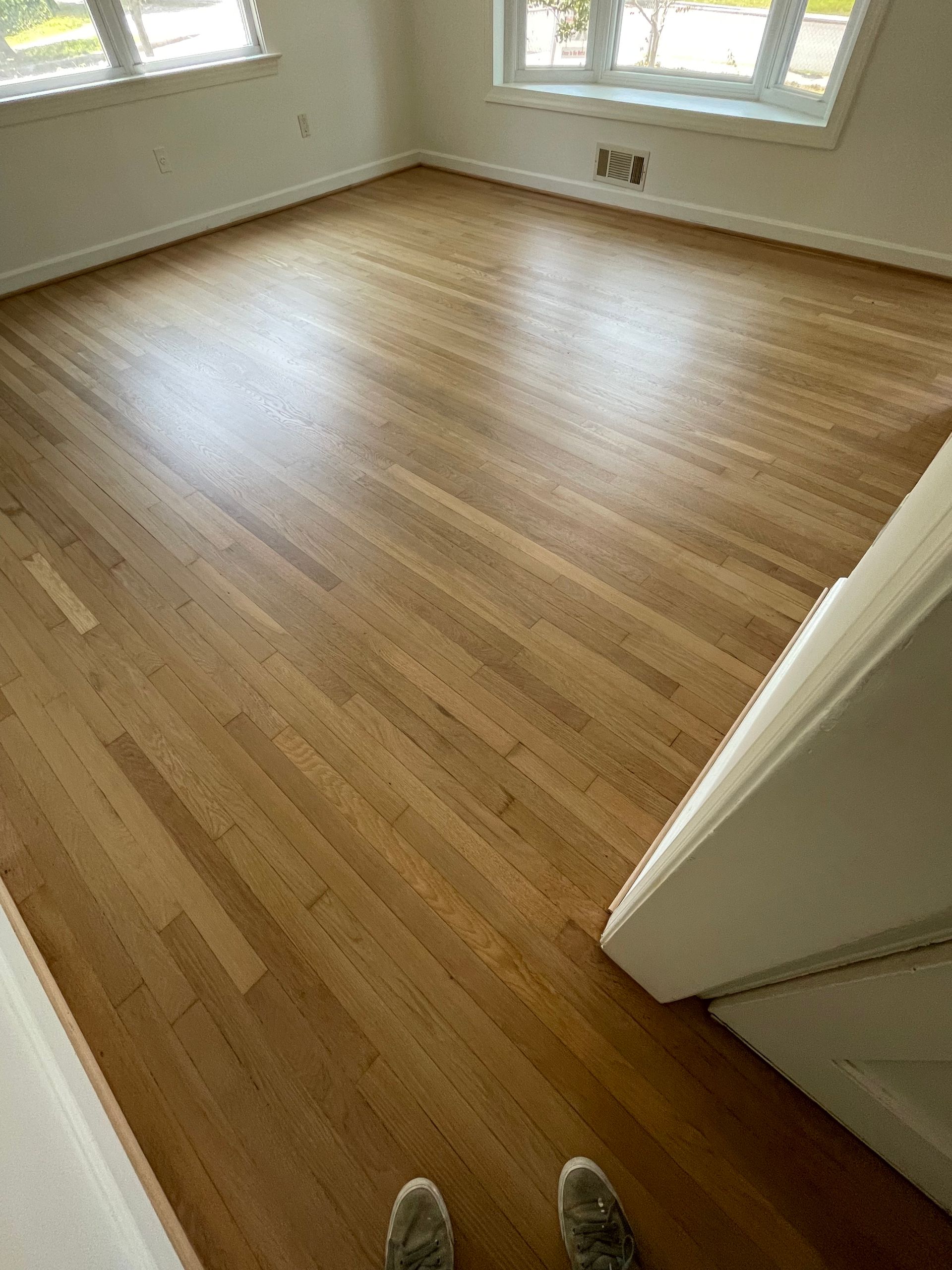 A person is standing on a wooden floor in a living room.