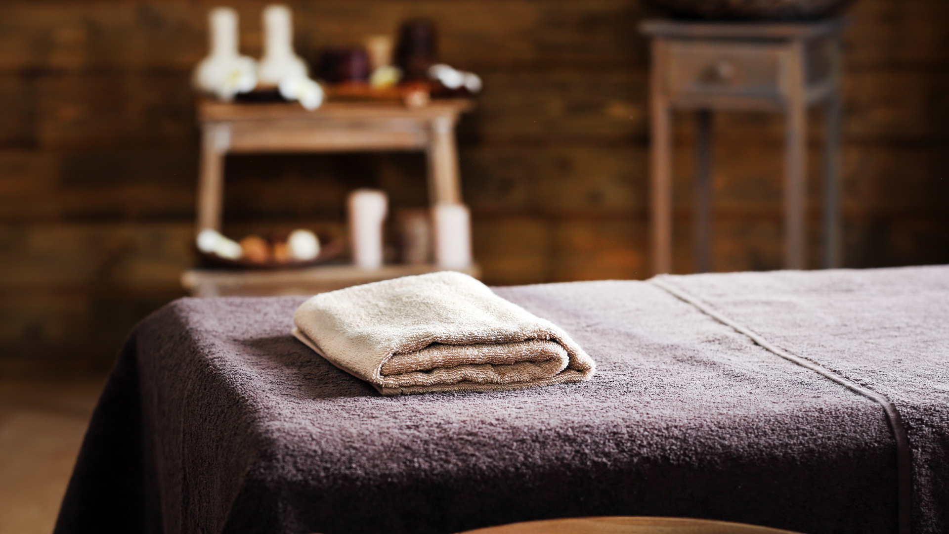 Folded towel on a massage table in a dimly lit spa.