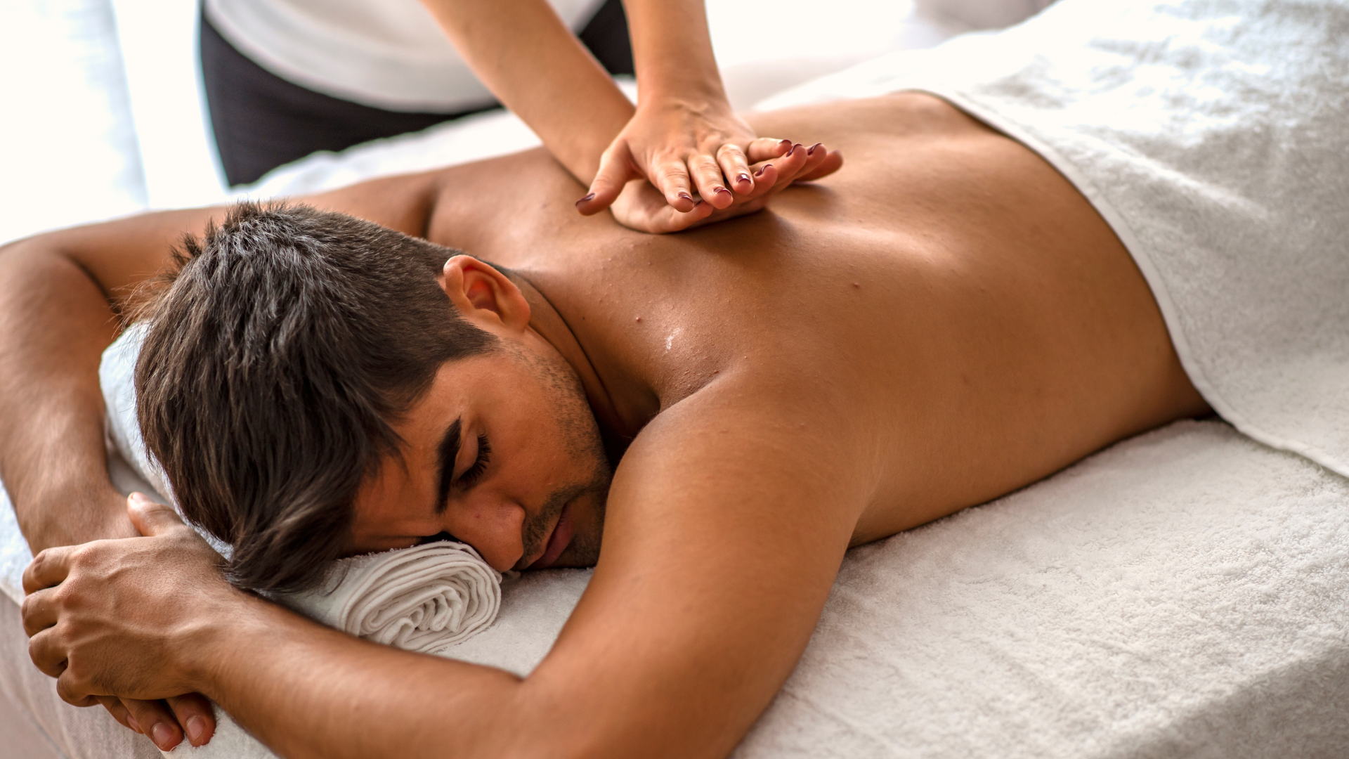 Man receiving back massage on a massage table. Hands of therapist applying pressure.
