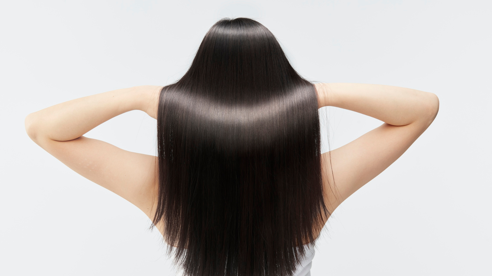 Person with long, straight, black hair, holding arms up, viewed from the back.